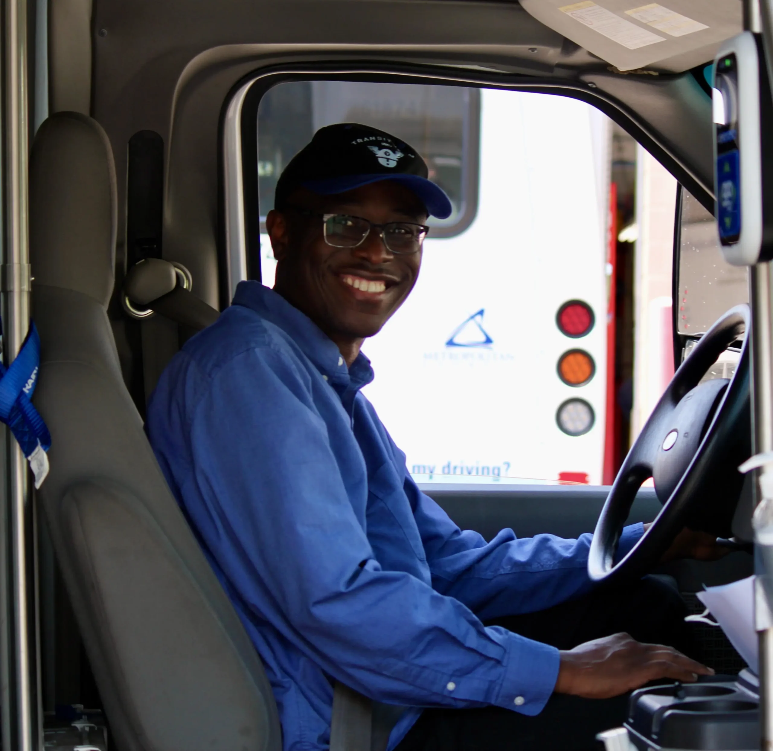 a bus driver sitting at the wheel and smiling