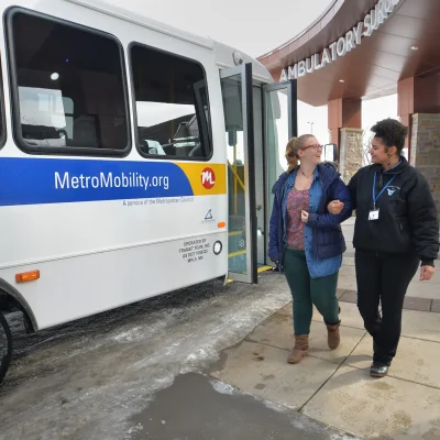 two women walking out of a white bus