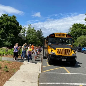 a group of people standing next to a school bus